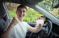 Happy and proud guy showing his driver license out of the car window, keeps fist up tight as a winner celebrating victory. Passing Royalty Free Stock Photo