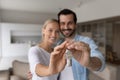 Happy proud millennial couple holding, showing keys, smiling at camera