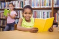 Happy pupil reading a library book