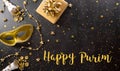 Happy Purim carnival decoration concept made from golden mask, wine, gift box and sparkle star on dark background.