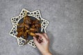 happy ramadan or eid concept, deglet nour algeria dates in stars plate, hand holding one piece.