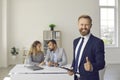 Happy real estate agent or mortgage broker standing in office, smiling and giving thumbs up Royalty Free Stock Photo