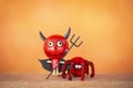 Happy red devil doll and red spider over blurred orange background Royalty Free Stock Photo