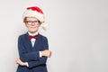 Happy red haired child boy in Santa hat standing against white wall background