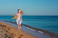 Happy red-haired child playing with an toy plane and running along the sandy beach of the sea against blue sky Royalty Free Stock Photo