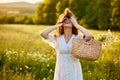 a happy red-haired woman in a light dress stands in a field and covers her face with her hair Royalty Free Stock Photo