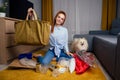 Happy redhaired ginger girl with spitz dog sorting waste:bottle,paper and plastic sitting at floor carpet in the living