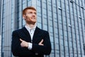 Happy redhead businessman with arms folded