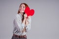 Happy redhead girl businesswoman in a striped shirt model sending air kiss with decorative hearts Valentines Day gift on Royalty Free Stock Photo