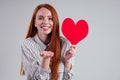 Happy redhead girl businesswoman in a striped shirt model sending air kiss with decorative hearts Valentines Day gift on Royalty Free Stock Photo