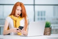 Happy redhead girl send an sms message to friend while working at modern office Royalty Free Stock Photo