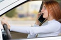 Happy redhead girl talking on her mobile phone behind the wheel driving a car Royalty Free Stock Photo