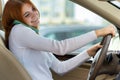 Happy redhead girl talking on her mobile phone behind the wheel driving a car Royalty Free Stock Photo