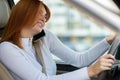 Happy redhead girl talking on her mobile phone behind the wheel driving a car Royalty Free Stock Photo