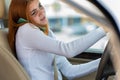 Happy redhead girl talking on her mobile phone behind the wheel driving a car Royalty Free Stock Photo