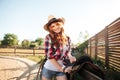 Happy redhead woman cowgirl preparing saddle for riding horse Royalty Free Stock Photo