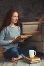 Happy redhead woman relaxing at home in cozy winter or autumn weekend with book Royalty Free Stock Photo