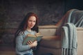 Happy redhead woman relaxing at home in cozy winter or autumn weekend with book Royalty Free Stock Photo