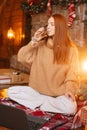 Happy redhead young woman drinking champagne during online Christmas or New year celebration Royalty Free Stock Photo