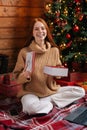 Happy redhead young woman getting Christmas gift box with present on background of xmas tree. Royalty Free Stock Photo