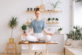 Happy redhead young woman is meditating while sits with closed eyes on desk