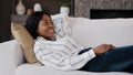 Happy relaxed african american woman rest lounge lying on couch enjoy peaceful mood weekend casual rest in living room Royalty Free Stock Photo