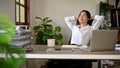 A happy and relaxed Asian businesswoman is leaning on her chair, putting hands behind her head Royalty Free Stock Photo