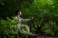 A happy Asian male hiker sits on a rock, taking a deep breath, enjoying nature while resting Royalty Free Stock Photo