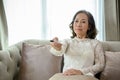 A happy and relaxed Asian middle-aged woman is on the sofa watching a game show on TV Royalty Free Stock Photo
