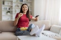 Happy relaxed asian woman watching tv and eating popcorn at home Royalty Free Stock Photo