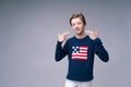 Happy relaxed contented handsome young man standing in blue sweater with usa