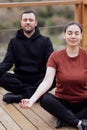 Happy relaxed man and woman doing yoga outdoors. Smiling sportsman sitting in lotus pose Royalty Free Stock Photo