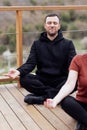 Happy relaxed man and woman doing yoga outdoors. Smiling sportsman sitting in lotus pose Royalty Free Stock Photo