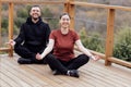 Happy relaxed man and woman doing yoga outdoors. Smiling sportsman sitting in lotus pose Royalty Free Stock Photo