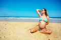 Pregnant woman in sunshades on beach touching hair Royalty Free Stock Photo