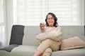 Happy and relaxed 60s retired Asian woman wearing glasses, watching TV in her living room Royalty Free Stock Photo
