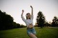 Happy teenage woman wearing headphones dancing on park lawn Royalty Free Stock Photo