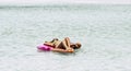 Happy and relaxed woman with bikini lay down on a coloured lilo at the beach enjoying the blue transparent amazing water in summer