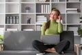 Happy and relaxed young Asian woman listening to music through her headphones on a sofa in her living room. Royalty Free Stock Photo