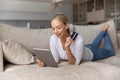 Happy relaxed young woman shopping using digital tablet. Royalty Free Stock Photo