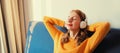Happy relaxed young woman listening to music with headphones lies on couch at home Royalty Free Stock Photo