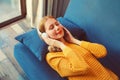 Happy relaxed young woman listening to music with wireless headphones with closed eyes lies on the couch at home Royalty Free Stock Photo