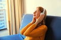 Happy relaxed young woman listening to music with wireless headphones with closed eyes lies on the couch at home Royalty Free Stock Photo