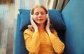 Happy relaxed young woman listening to music with wireless headphones with closed eyes lies on the couch at home Royalty Free Stock Photo