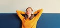 Happy relaxed young woman listening to music with wireless headphones with closed eyes lies on the couch at home Royalty Free Stock Photo