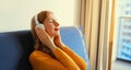 Happy relaxed young woman listening to music with wireless headphones with closed eyes lies on the couch at home Royalty Free Stock Photo