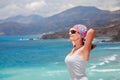 Happy relaxing woman standing with arms behind head smiling