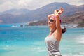 Happy relaxing woman standing with arms raising up behind head smiling.