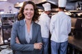 Happy restaurant manager standing with arms crossed in commercial kitchen Royalty Free Stock Photo