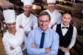 Happy restaurant team standing together with arms crossed in commercial kitchen